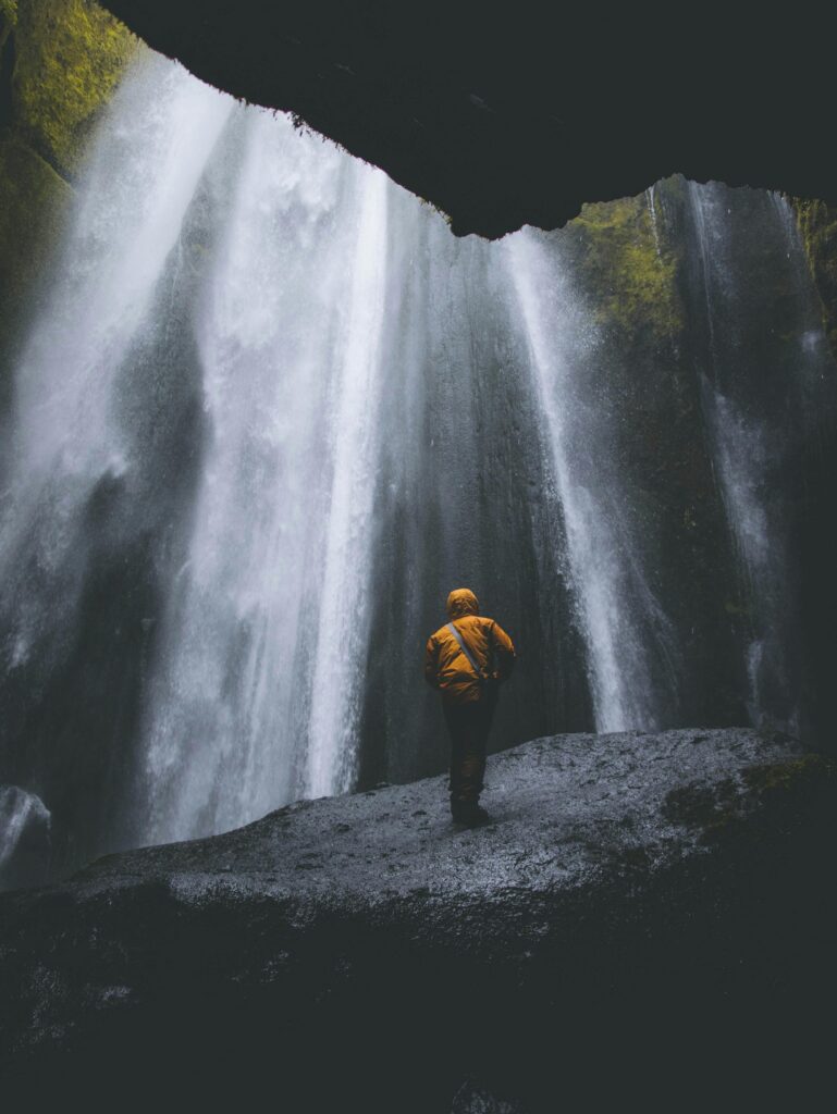 Photo d'un homme devant une cascade magnifique